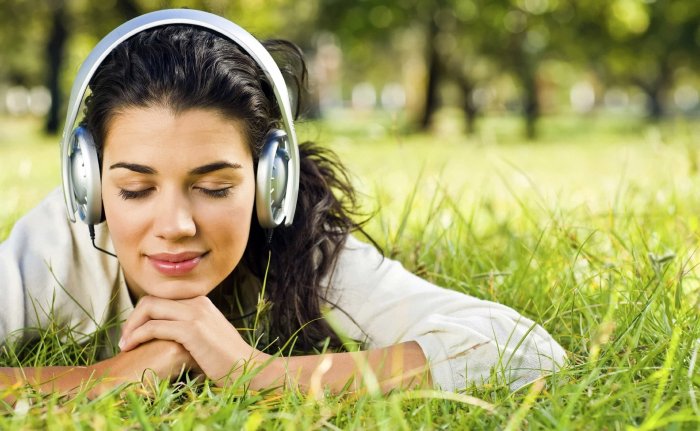 The girl listens to the sound of grass in the headphones
