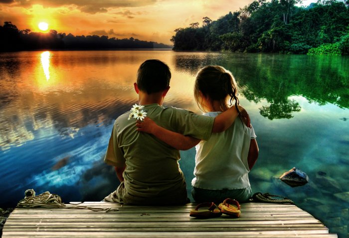 A boy and a girl are sitting by the pond