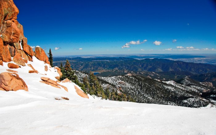 Вид на покрытые лесом горы со снежной вершине