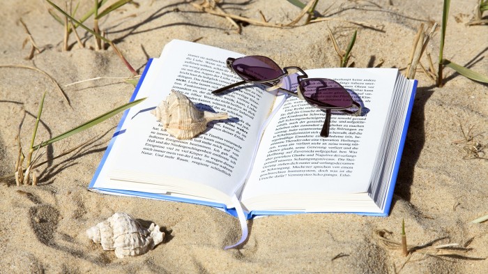The book is on the sand, the glassesis on the book
